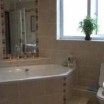 Main bathroom with corner bath and tiled walls